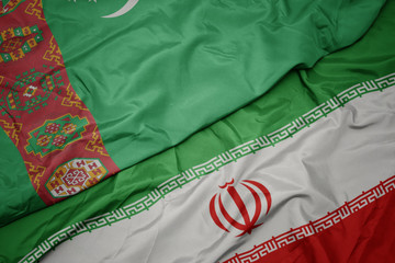 waving colorful flag of iran and national flag of turkmenistan.