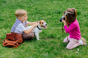 Cute clever little girl photographing handsome blond older boy