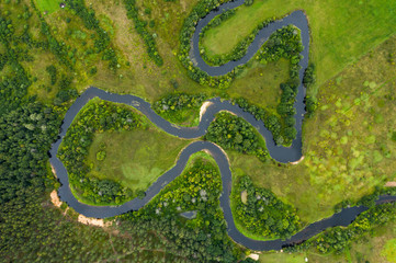 Top view drone shot of a green field, forest and river