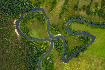 Top view drone shot of a green field, forest and river