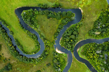 Top view drone shot of a green field, forest and river