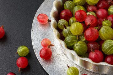 Gooseberries in a metal baking pan on a black background