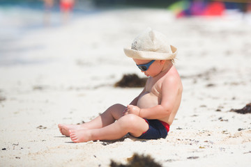 Cute baby boy playing with beach toys on tropical beach