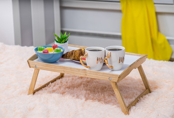 Romantic breakfast on the tray  on the bed. Coffee and food.