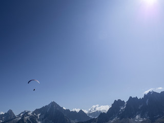 Fototapeta na wymiar One Parachoutte in the blue sky with clouds in the French Alps, Chamonix during a summer tour, fly and sport.