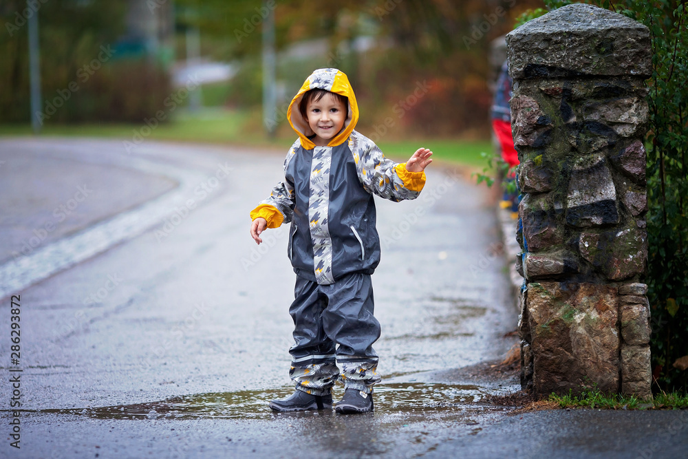 Poster Cute boy in the park, playing in the rain, jumping in puddles