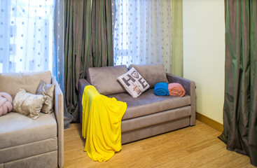 Modern interior of light living room. Cozy sofa. Yellow plaid.