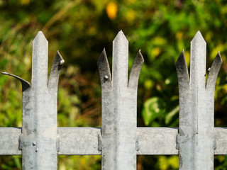 Anti climbing metal fence topping, green forest in the background. totally legal. Concept security,...