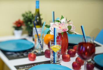 Close-up of served table. Red wine glasses. Water in glass. Wine bottle. Apples.