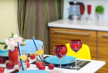 Close-up of served table. Red wine glasses. Water in glass. Wine bottle. Apples.