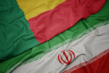 waving colorful flag of iran and national flag of benin.