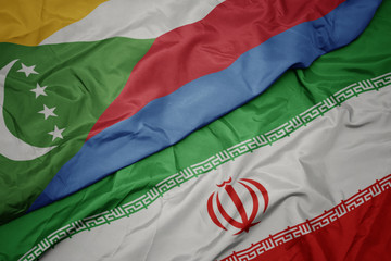 waving colorful flag of iran and national flag of comoros.