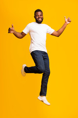 Fototapeta na wymiar Happy african american man jumping and showing thumbs up
