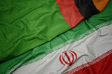 waving colorful flag of iran and national flag of zambia.