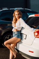 Obraz na płótnie Canvas young pretty woman in sexy denim shorts near cars