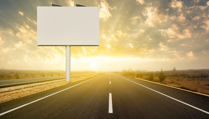 Blank billboard on highway at sunset