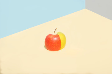 multi-colored apple with green and red, folded from halves. On a gray-blue background. Creative minimalism
