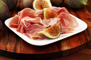 Italian prosciutto crudo or jamon with sliced figs Raw ham.