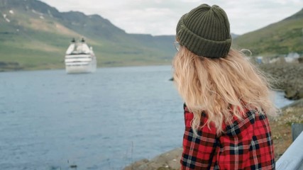 Young woman sits in port watch cruise ship leave