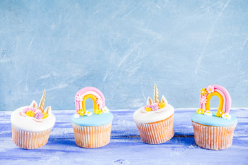 Cute unicorn and rainbow cupcakes, light blue background, copy space