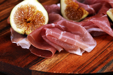 Italian prosciutto crudo or jamon with sliced figs Raw ham.