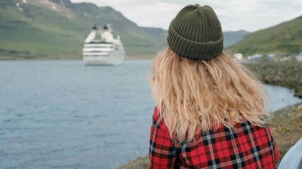 Young woman sits in port watch cruise ship leave