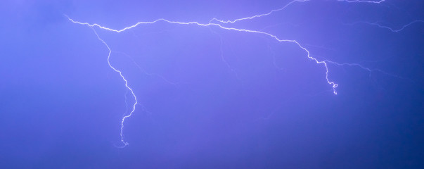 Long lightning bolt with side branches is high up in the sky