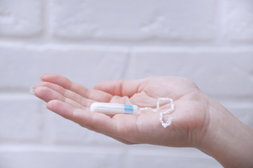 Girl tampon in hand closeup on a light background.