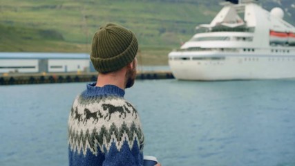 Hipster bearded man in sweater next to cruise ship