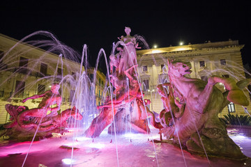 Night view of the colorful and illuminated Diana's fountain in Piazza Archimede in Syracuse, Sicily Italy. - obrazy, fototapety, plakaty