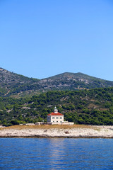 Fototapeta na wymiar Picturesque lighthouse on a small island near town Hvar, on island Hvar, Croatia.