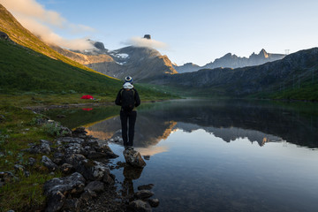 Tourist watching the beautiful reflection of Romsdal horn in the lake Vengedalsvatnet.
