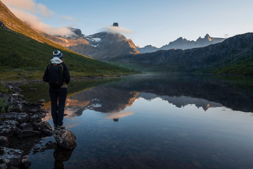 Tourist watching the beautiful reflection of Romsdal horn in the lake Vengedalsvatnet.
