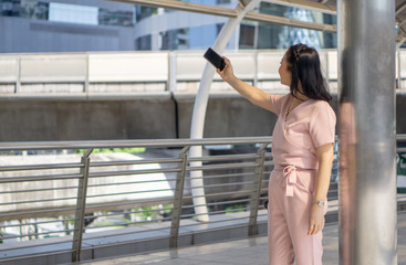 Healthy middle-aged women look happy wearing pink pants outdoor ambience with modern communication tools, smartphone