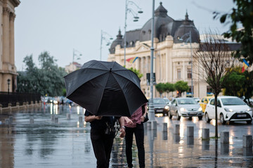 People with black umbrella in the rain at Calea victoriei square