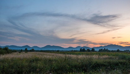 Obraz premium Clouds in the sky in the form of letters SS. Sunset landscape with silhouettes of mountains and fog. Fog in the valley