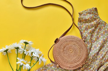 Summer fashion background, flat lay with summer dress, round rattan bag, white flowers.