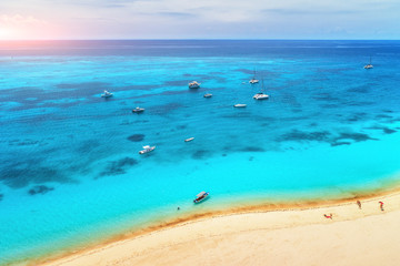 Aerial view of boats and yachts on tropical sea coast with white sandy beach at sunset in summer. Indian Ocean in Africa. Landscape with boat, people, transparent azure water, sky. Top view. Holidays