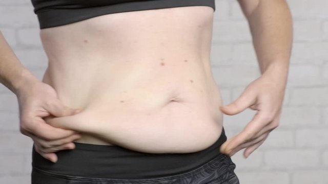 fat flabby belly in adult woman close-up. 