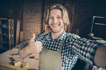 Self-portrait of his he nice handsome cheerful cheery positive content guy wearing checked shirt uniform showing thumbup recommend at industrial brick loft style interior studio