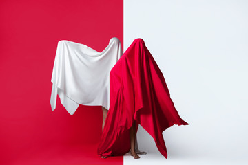 Female figures in fluttering in the wind fabrics. Red and white silhouette on a red background in the Studio. Minimalism. Concept