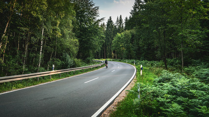 Fototapeta na wymiar Bike on Long Curvy Forest Road In Alpine Mountains