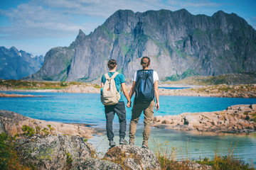 Two girls stand holding hands on the background of the Lofoten Islands, traveling to Norway,...