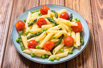 Penne pasta salad with asparagus , tomatoes and peas