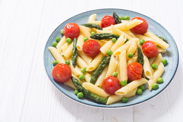 Penne pasta salad with asparagus , tomatoes and peas