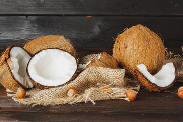 Broken coconut on a dark aged wooden table close up