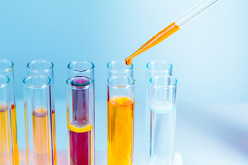 Laboratory test tubes with red and yellow liquids on light blue background