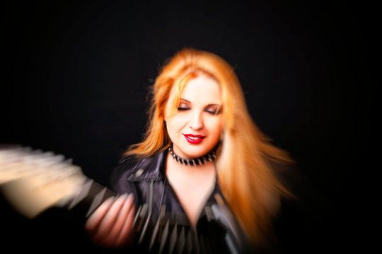 Beautiful blonde girl in rock style on a black background. Blur motion effect.