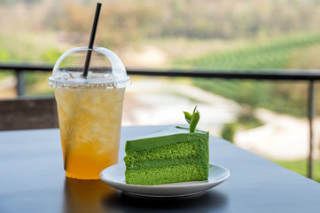 Green tea cheesecake with ice thai tea drink on table