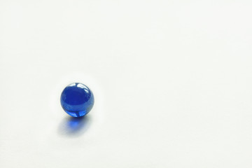 Glass ball of blue color on a white background. Copy space. Abstract background. Shallow depth of field (DOF)